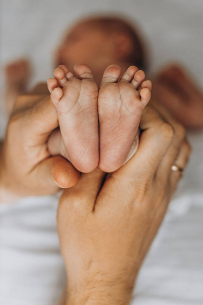 Portrait of beautiful little legs with tiny fingers, of adorable newborn baby girl, in caring parent arms, happy family moments, birth and childhood concept - Fotoğraf, Görsel