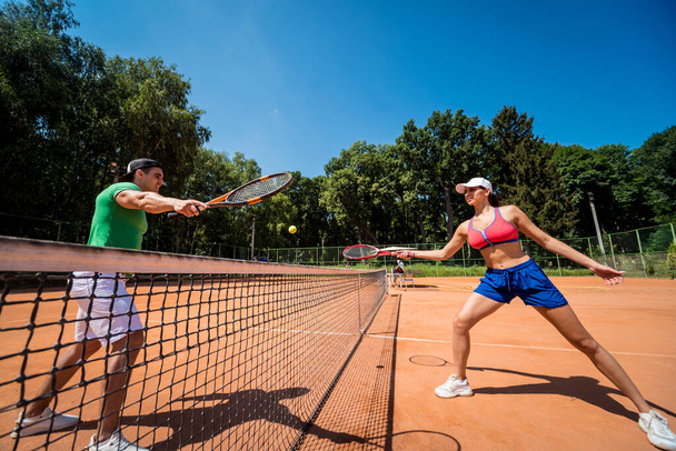 Young athletic couple playing tennis on the court. - Φωτογραφία, εικόνα