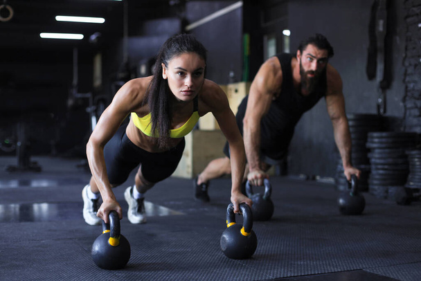 Sporty man and woman doing push-up in a gym - Foto, imagen