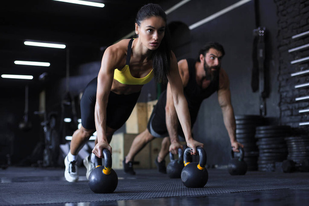 Sporty indian man and woman doing push-up in a gym - Zdjęcie, obraz