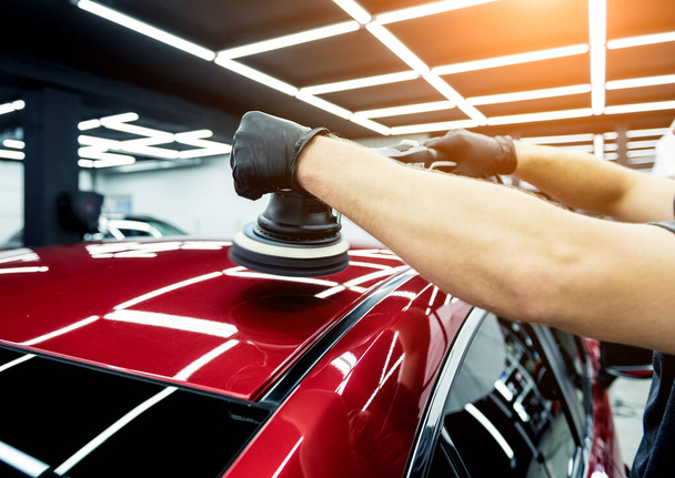 Car service worker polishes a car details with orbital polisher. - Foto, imagen