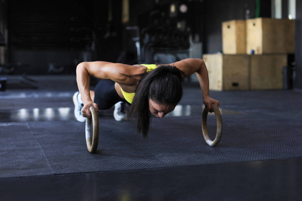 Sporty strong woman doing push-ups on rings - Fotó, kép