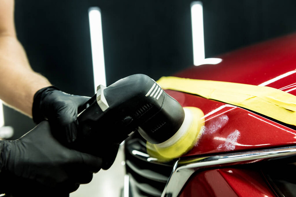 Car service worker polishes a car details with orbital polisher. - Фото, зображення