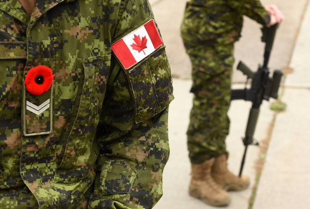 Flag of Canada on the military uniform and soldier with weapon on the background. Canadian soldiers. Canadian Army. Remembrance Day.Poppy day.  - Foto, afbeelding