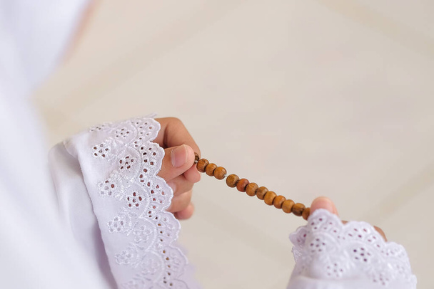 Mujer rezando con cuentas islámicas tradicionales en la mano y arrodillada en una mezquita. - Foto, Imagen