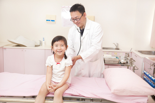 pediatra maschio esaminando bambina in clinica
 - Foto, immagini