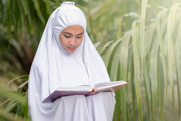 Hermosas mujeres musulmanas sosteniendo el Corán en un jardín de árboles verdes, concepto de educación musulmana - Foto, Imagen