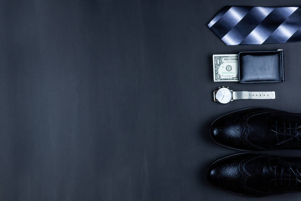 Business flat lay background with a copy space. Male shoes, wrist watch wallet,  belt, mobile phone and a necktie on black  background. - Foto, Imagen