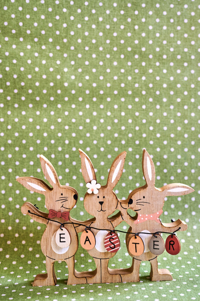 Три дерев'яні великодні кролики з розписаними прикрасами і текстом Великодня написані на яйцях
. - Фото, зображення