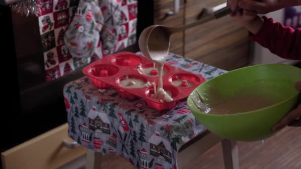 Weihnachten, Winter, Neujahr, Feiern, Familie, Backen, Zubereiten, Kochkonzept - Junge Mutter bereitet mit ihrem kleinen Sohn in der weihnachtlich dekorierten Küche Gebäck zu - Filmmaterial, Video