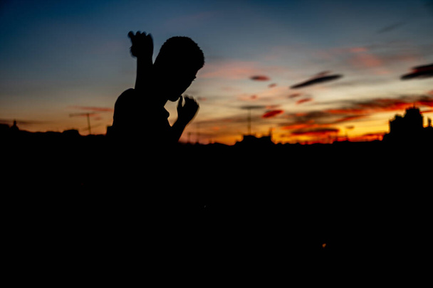 後ろにカラフルな夕日の少年のシルエット - 写真・画像