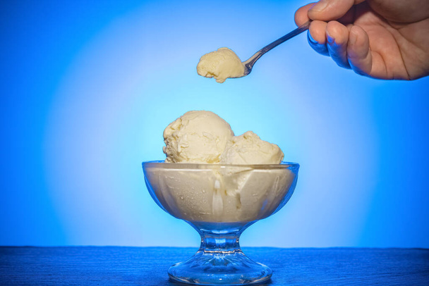 mangiare tazza di gelato e cubetti di ghiaccio su sfondo blu retroilluminato - Foto, immagini