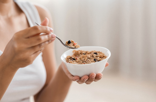 Gesneden foto van vrouw met kom met zelfgemaakte granola - Foto, afbeelding