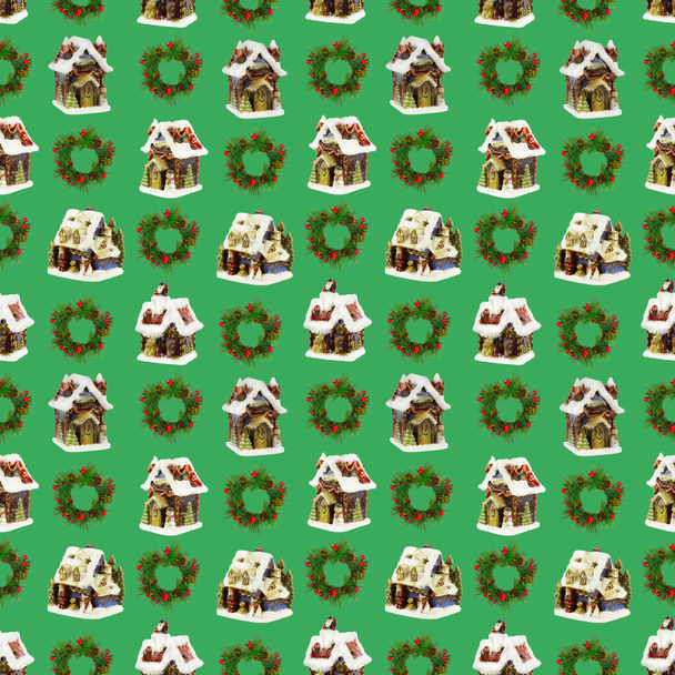 Un patrón sin costuras, casas de Navidad y coronas de ramas de abeto sobre un fondo verde claro. - Foto, imagen