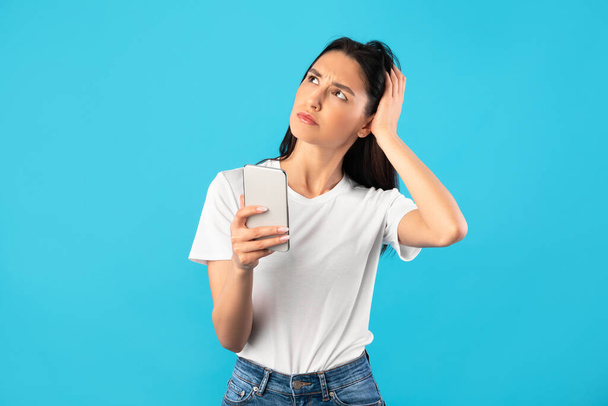 Confused upset young woman holding mobile phone - Photo, image