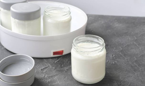 homemade yogurt making, glass jars with kefir. fermented dairy product made in yogurt making machine. probiotic food for gut health. good digestion concept.  - Photo, Image