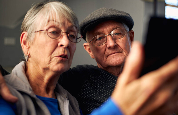 Oudere paar thuis het maken van video-oproep naar familie op mobiele telefoon - Foto, afbeelding