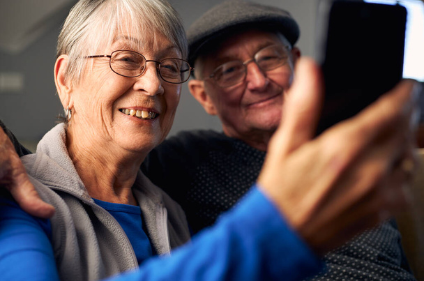 Couple âgé à la maison faisant un appel vidéo à la famille sur téléphone mobile - Photo, image