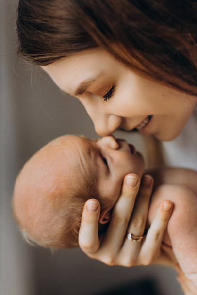 Adorable woman hold newborn baby girl in arms, caring mother with little daughter gently touch with noses, smiling, enjoy tender parenting moments, maternity concept - Foto, Imagem