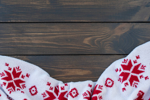 cuadros blancos de punto con el patrón tradicional de Navidad con copos de nieve se encuentran arrugados sobre fondo de madera oscura. Copiar espacio para texto. - Foto, Imagen