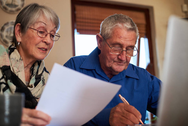 Oudere paar thuis controleren van persoonlijke financiën op laptop - Foto, afbeelding