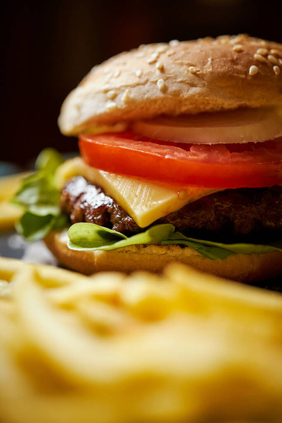 délicieux cheeseburger entouré de frites sur une table noire - Photo, image