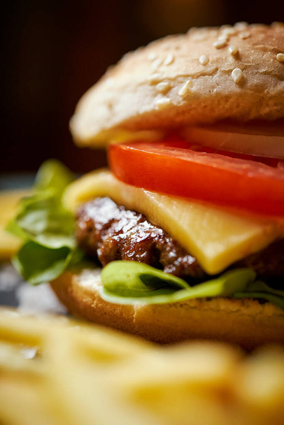 köstlicher Cheeseburger umgeben von Pommes auf einem schwarzen Tisch - Foto, Bild