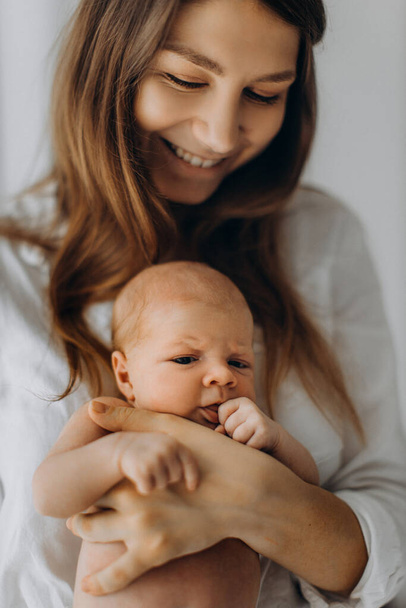 Gorgeous woman hold newborn baby girl in arms, happy mom enjoy tender parenting moments with little daughter, smiling, motherhood concept - Foto, immagini