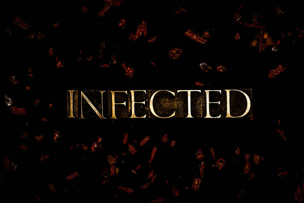 Infected text in flaming copper letters on black background with bright red floating particles - Photo, Image