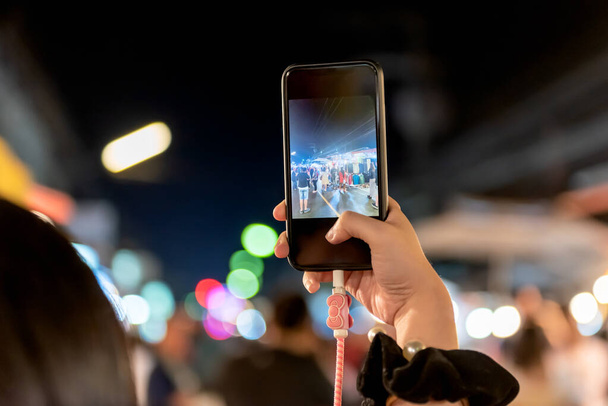 Люди, які користуються мобільними телефонами Фотографування туристів На нічному ринку, який подорожує пам'ятки в Таїланді, до технології і концепції застосування. - Фото, зображення