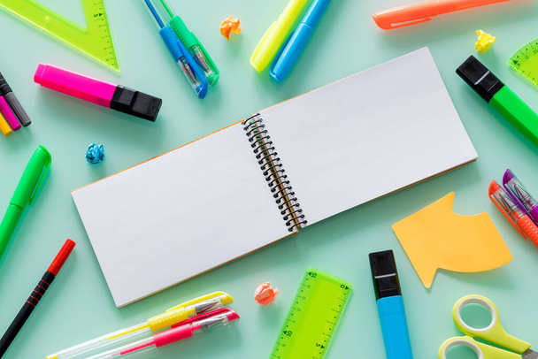 school en kantoor items, gekleurde pennen, nietjes, viltstiften, set pleinen, een blanco notitieboekje voor uw eigen tekst in het centrum. - Foto, afbeelding