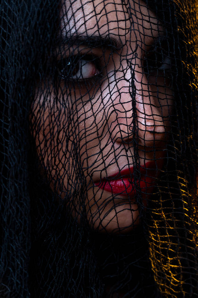 Portrait of a young sad woman with black veil and red lips - Foto, Imagen