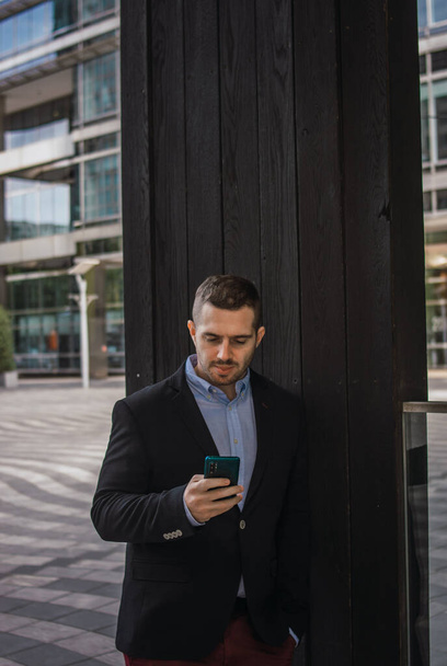 Photo of a young and attractive business man checking his phone. Wearing smart casual clothes. Entrepeneur style - Foto, Bild