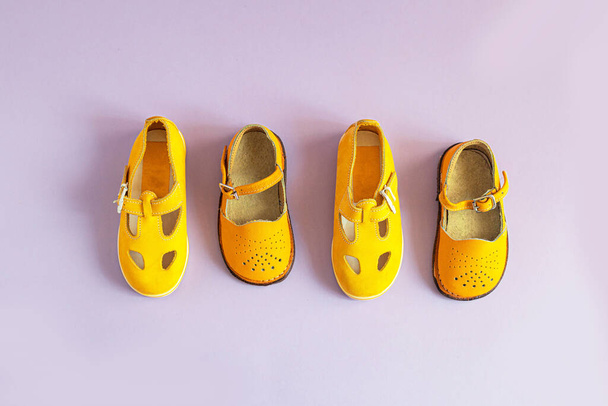 Jasně žluté dětské boty na šeříkovém pozadí s kopírovacím prostorem. Koncept dětského oblečení. Pohled shora, byt ležel - Fotografie, Obrázek