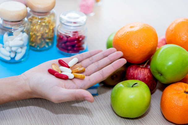 Close-up beelden van voedingsdeskundigen worden getoond Vitaminen pillen, die geëxtraheerd uit verschillende vruchten te zijn en alternatief en versterking van de immuniteit tegen het coronavirus voor de gezondheid concept. - Foto, afbeelding