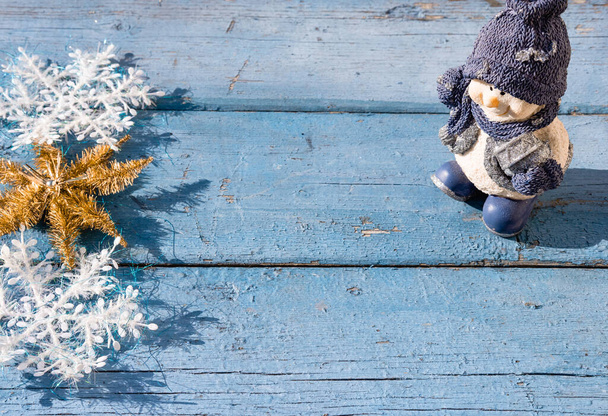 Gyönyörű kék karácsonyi vízszintes háttér egy hóember, fehér hópelyhek és egy arany fényes csillag. Fából készült karácsonyi háttér, felülnézet. A szöveg helye az új év hátterében. - Fotó, kép