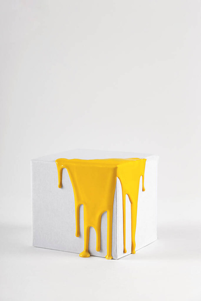 Cubo blanco con manchas de pintura amarilla brillante - Foto, Imagen