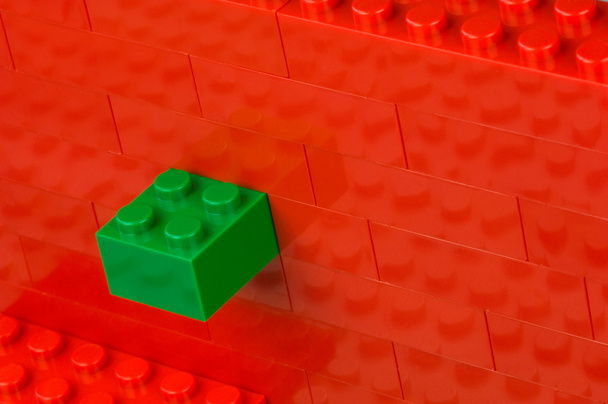 Bloque de construcción verde en una pared de color rojo
 - Foto, Imagen
