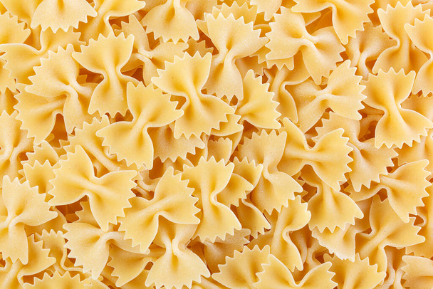 Variety of types and shapes of Italian pasta. Dry pasta background. A portion of Farfalle bows pasta isolated on white. Heap of bow tie pasta isolated on white background. - Photo, image