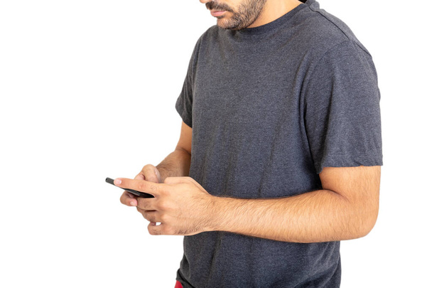 Młody człowiek w szarej koszuli patrzy na telefon odizolowany na białym tle. Zwykła odzież męska, reklama szablonu - Zdjęcie, obraz