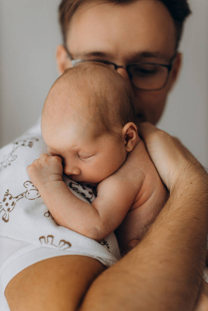 Handsome man hold adorable newborn baby girl in arms, caring dad look with love at the little daughter, enjoy tender parenting moments, fatherhood concept - 写真・画像