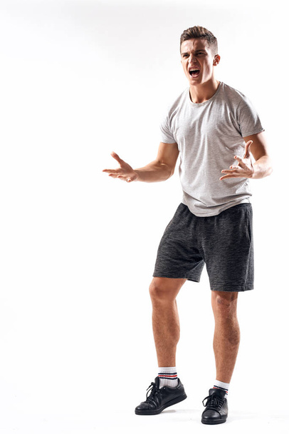 Hombre atlético sobre un fondo claro en pleno crecimiento y jogging pantalones cortos de carga zapatillas camiseta - Foto, Imagen
