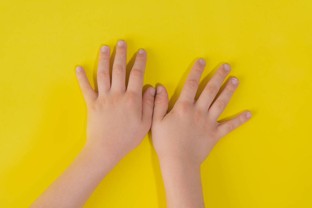 Child hands on yellow background - 写真・画像