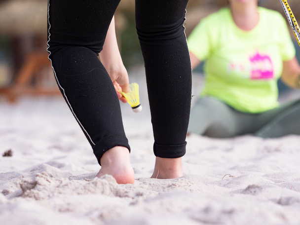 Hezké ženy hrající badminton na pláži. Bílý písek u moře. Časný ranní trénink před celodenním sluněním. - Fotografie, Obrázek