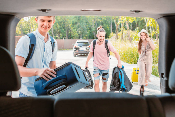 friends load car trunk with baggage. summer road trip vacation. - Fotoğraf, Görsel