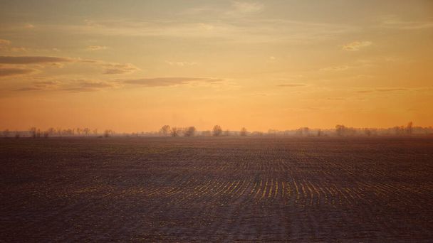 Закат над сельскохозяйственной равниной. Вечером фермерские поля. Простой пейзаж. - Фото, изображение