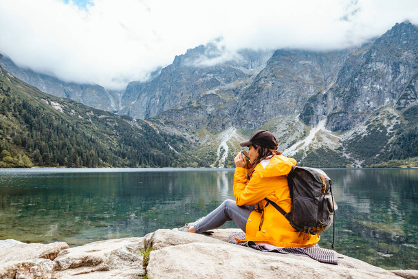 žena batohem sedí na skále s výhledem na jezero v Tatra National Park hory. kopírovat prostor - Fotografie, Obrázek