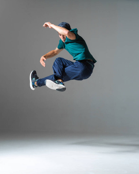 Cool man breakdancer jumps dancing hip-hop isolated on gray background. Dance school poster. Break dance lessons - Photo, image