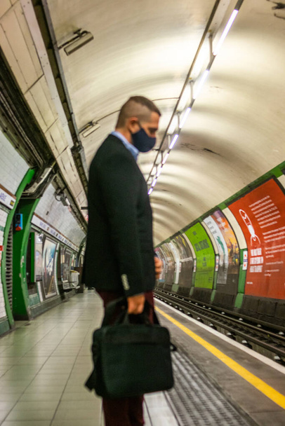 Фото молодого и привлекательного бизнесмена в элегантной повседневной одежде, ждущего, чтобы заставить метро ездить на работу - Фото, изображение