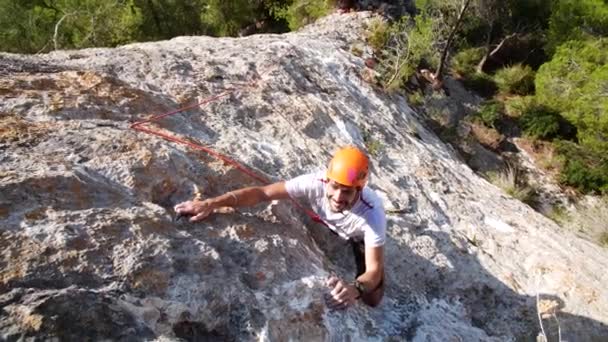 Man lead climbing in nature rock, next to sea, in Andratx coastline, Mallorca island, Spain.Low angle, twist movement, 4K 60p. - Filmagem, Vídeo
